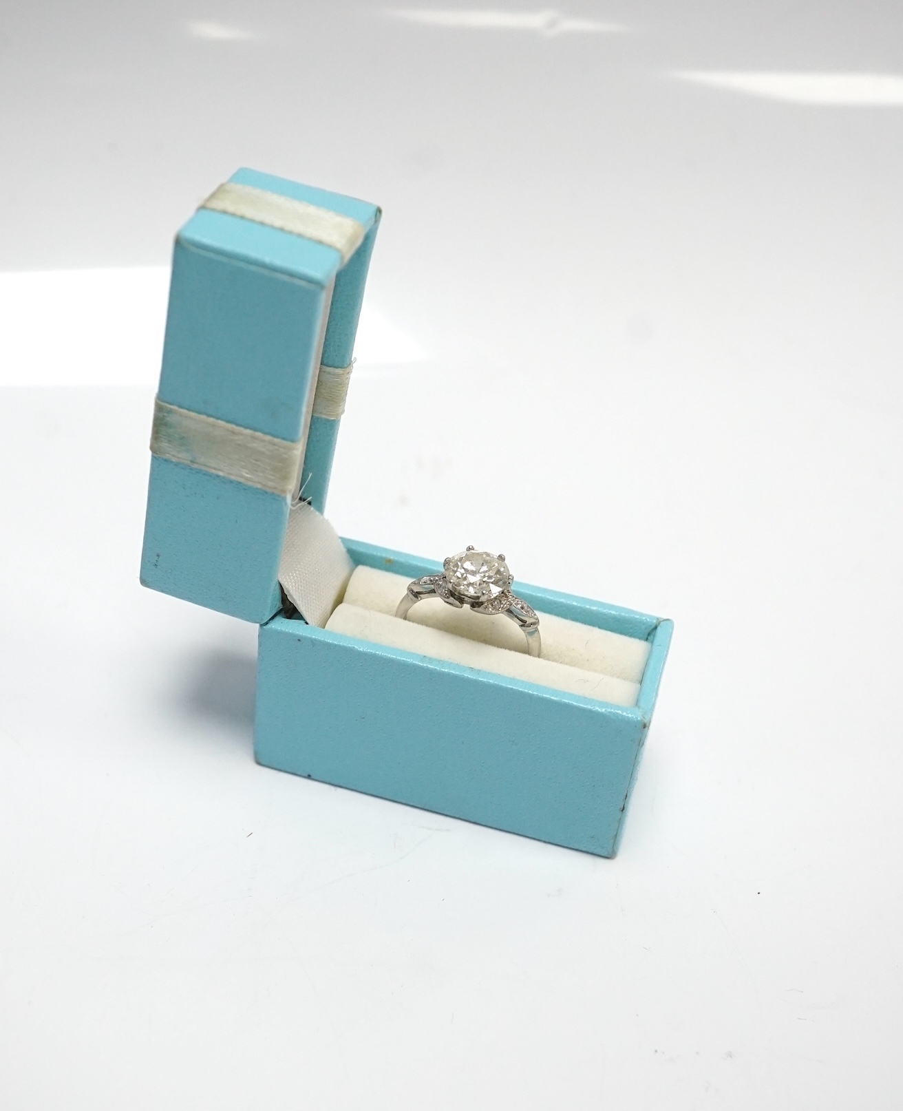 A platinum and single stone diamond set ring, with six stone diamond chip set foliate shoulders, the centre stone weighing 1.60ct, size H/I, gross weight 3.1 grams. Condition - fair